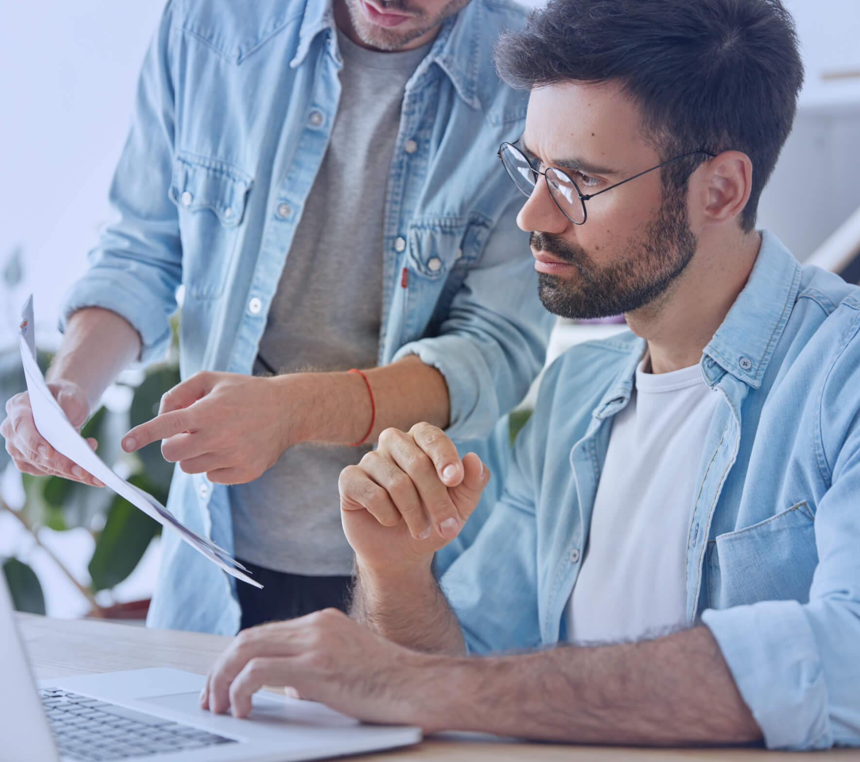 Two men working on a laptop computer together.